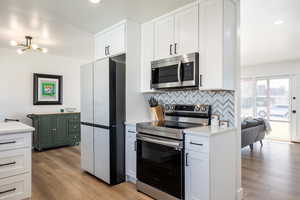 Kitchen with white cabinetry,  tasteful backsplash, light stone counters