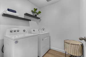 Laundry room with light wood-type flooring and separate washer and dryer