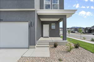 Property entrance with covered porch, a residential view, stucco siding, and a garage