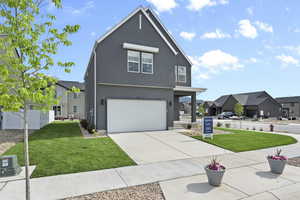 View of front of property featuring a front lawn, stucco siding, a garage, concrete driveway, and a residential view