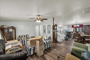 Living area featuring suspended lighting, dark wood-type flooring, a textured ceiling, and ceiling fan