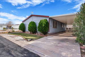 View of home's exterior featuring an attached carport, driveway, and a yard