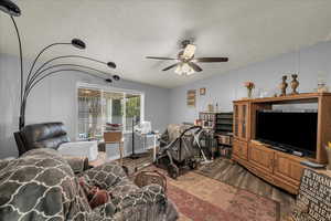 Living room with ceiling fan, dark wood finished floors, and a desk