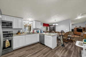Kitchen featuring a peninsula, suspended lighting, and white cabinetry