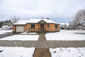 View of front of house with brick siding, a garage, a chimney, and driveway