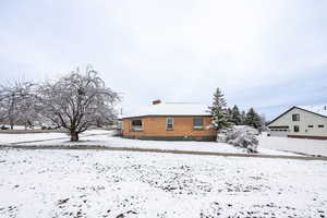 Snow covered back of property with a chimney