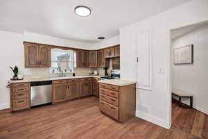 Kitchen featuring light countertops, dishwasher, dark wood-style flooring, and range with electric cooktop