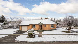 View of front of house featuring an attached garage, brick siding, driveway, and a chimney