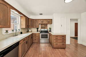 Kitchen featuring stainless steel appliances, light countertops, light wood-like floors, and wood finish cabinetry