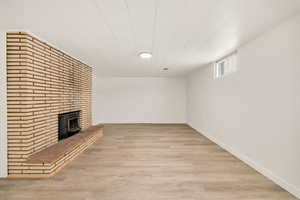 Basement with laminate flooring, baseboards and a fireplace