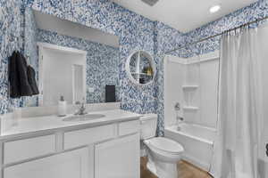 Bathroom featuring vanity, shower / bathtub combination with curtain, light wood finished floors, and wallpapered walls