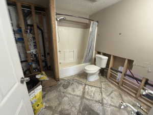 Bathroom featuring shower / bath combo with shower curtain and a textured ceiling