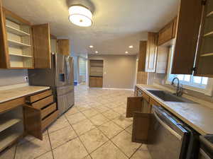 Kitchen featuring open shelves, light countertops, stainless steel dishwasher, recessed lighting, and wood finish cabinetry