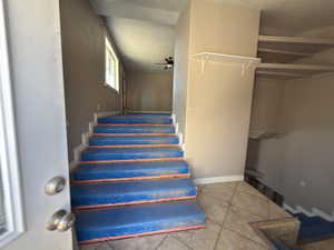Stairs with tile patterned floors and a ceiling fan
