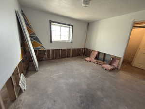 Unfurnished room featuring unfinished concrete floors and a textured ceiling