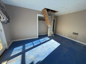 Unfurnished room featuring dark colored carpet and baseboards