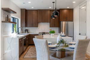 Kitchen featuring open shelves, light stone countertops, dark wood finish cabinets, stainless steel appliances, and light wood-style flooring