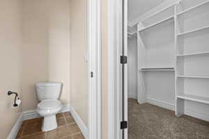 Bathroom with a spacious closet and dark tile patterned floors