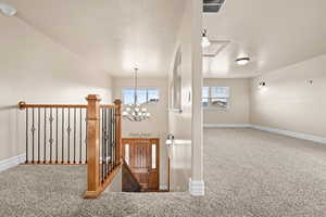 Stairway with carpet floors, a chandelier, healthy amount of natural light, and a textured ceiling