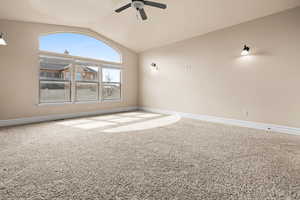 Carpeted empty room featuring lofted ceiling and a ceiling fan