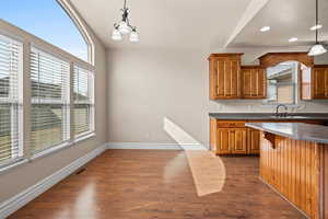 Kitchen with wood finish cabinetry, dark wood-style floors, a chandelier, and a breakfast bar