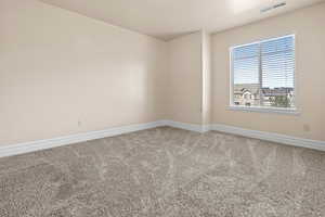Empty room with light colored carpet and baseboards