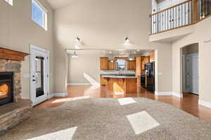Kitchen with open floor plan, a breakfast bar area, a fireplace, arched walkways, and a high ceiling