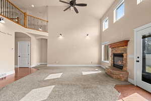 Unfurnished living room featuring a fireplace, a ceiling fan, carpet, arched walkways, and vaulted ceiling