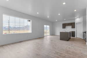Kitchen with a mountain view, a kitchen island with sink, open floor plan, light wood-type flooring, and dark wood finish cabinets