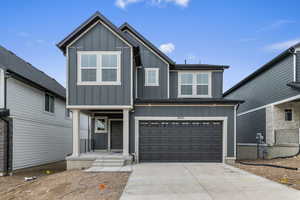 View of front of house with board and batten siding, an attached garage, and driveway