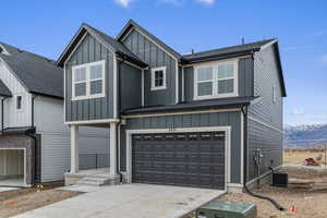 Modern inspired farmhouse with a garage, board and batten siding, concrete driveway, a mountain view, and a shingled roof