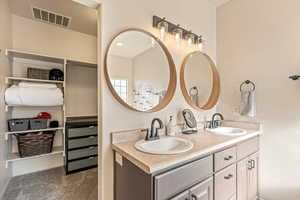 Full bathroom with double vanity, a spacious closet, and dark colored carpet