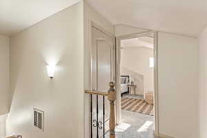 Hallway featuring light carpet and vaulted ceiling