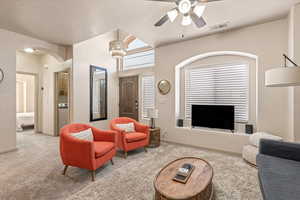 Living area with ceiling fan, carpet floors, and arched walkways
