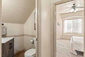 Ensuite bathroom featuring ceiling fan, vanity, and light carpet