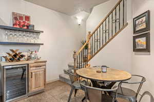 Indoor dry bar featuring open shelves, beverage cooler, and light wood finish cabinetry