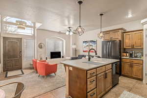 Kitchen featuring open floor plan, light countertops, freestanding refrigerator, an island with sink, and dishwashing machine