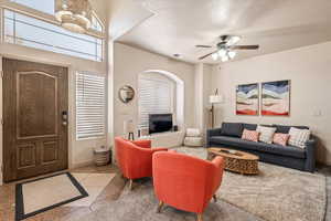 Living area with light tile patterned floors, suspended lighting, a ceiling fan, healthy amount of natural light, and a textured ceiling