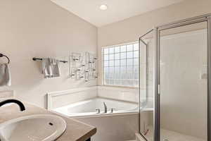 Full bathroom with double vanity, a stall shower, a bath, and recessed lighting