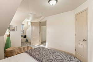 Bedroom featuring light carpet and lofted ceiling