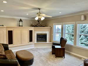 Formal Living area featuring a fireplace, new carpet, fireplace, ceiling fan, crown molding, and recessed lighting