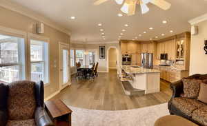 Great room featuring Gourmet Kitchen, crown molding, recessed lighting, arched walkways, a ceiling fan, and light wood & carpeted finished floors