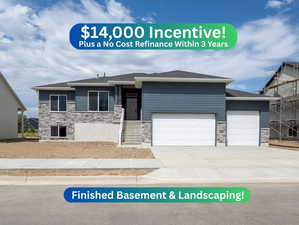 View of front of property featuring stone siding, an attached garage, and driveway