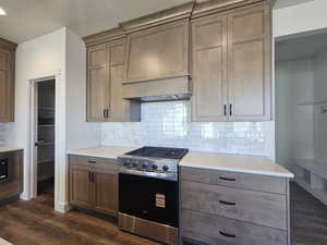 Kitchen featuring stainless steel range with gas stovetop, tasteful backsplash, dark wood-style floors, wood finish cabinetry, and recessed lighting