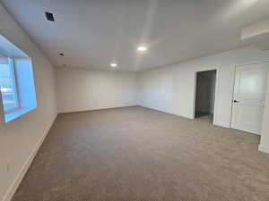 Carpeted empty room with baseboards and recessed lighting