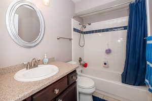 Bathroom with vanity, shower / bath combo with shower curtain, and light tile patterned flooring