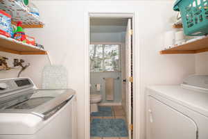 Laundry room with washing machine and dryer and light tile patterned floors