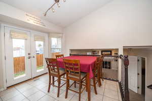 Dining space with french doors, vaulted ceiling, rail lighting, and light tile patterned flooring