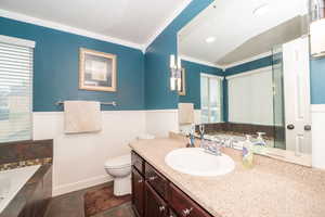 Full bathroom with a garden tub, vanity, and ornamental molding