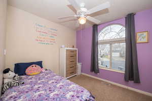 Bedroom with light carpet, ceiling fan, and a textured ceiling